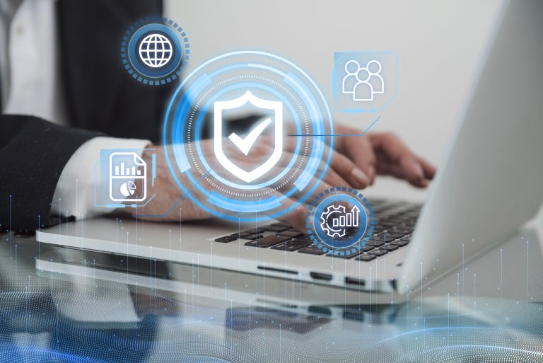 Início 18 Pessoa utilizando um laptop, com gráficos e ícones digitais flutuando sobre a imagem, incluindo um escudo com check, simbolizando proteção e segurança. A cena representa o conceito de cibersegurança bancária, destacando a importância de tecnologias avançadas para proteger dados financeiros, transações digitais e informações sensíveis contra ameaças cibernéticas.