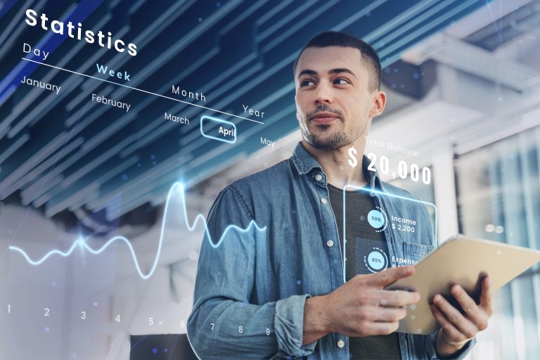 Início 2 Homem segurando um tablet enquanto observa gráficos financeiros digitais e estatísticas projetadas em realidade aumentada, incluindo dados de saldo e despesas. A imagem representa o uso de tecnologias modernas por fintechs para oferecer soluções inovadoras de gestão financeira e análise de dados em tempo real.